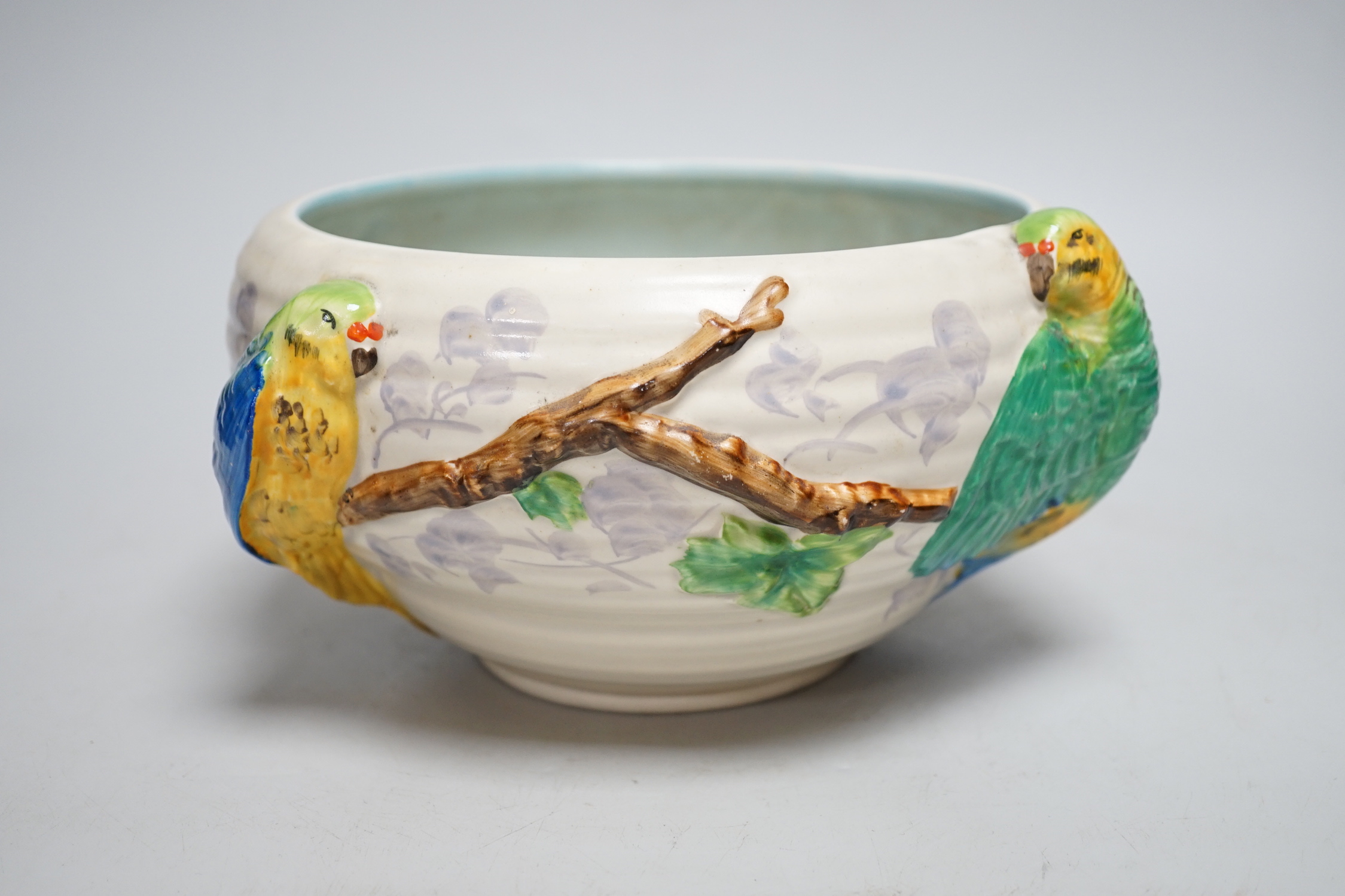 A late Clarice Cliff bowl with perched parrot decoration, 12cm tall